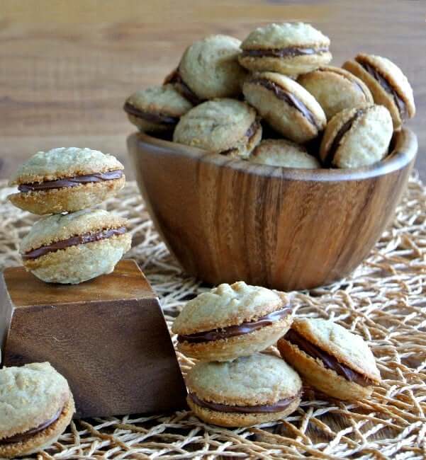 Sandwich Cookies are shaped oval on the top and the bottom and are filling a wooden bowl.