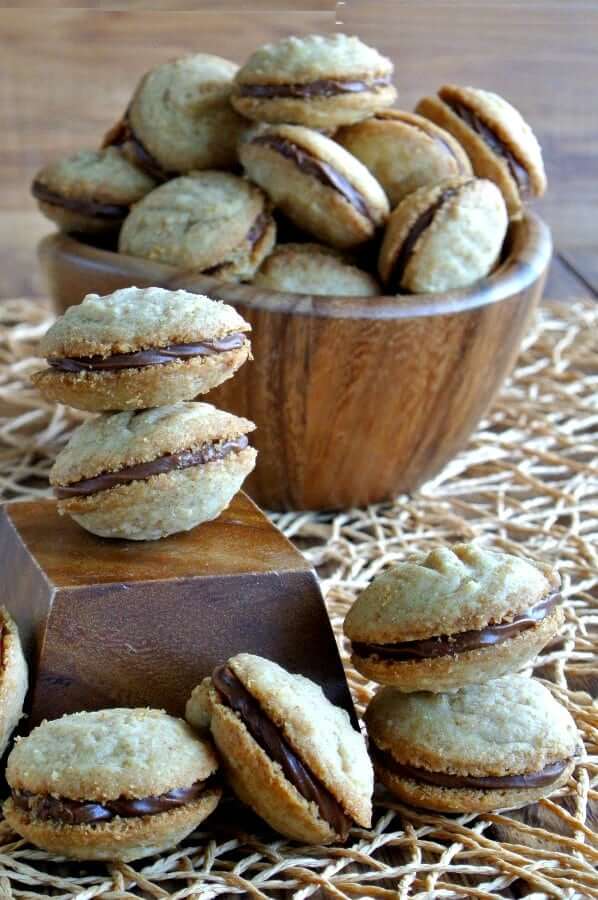 Chocolate filled shortbread sandwich cookies angles in all directions on a woven mat.