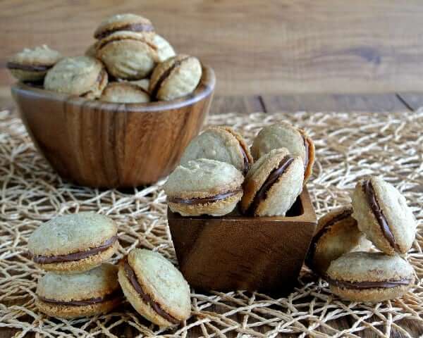 Shortbread cookies filled with chocolate frosting are piled into wooden bowls.