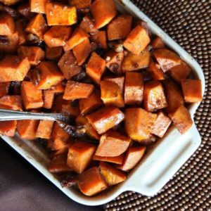 Close up square photo of baked sweet potato casserole with pecans.