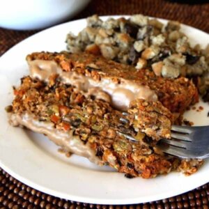 Two slices of Vegan Meatloaf with gravy and mushroom stuffing with a fork picking up a bite.