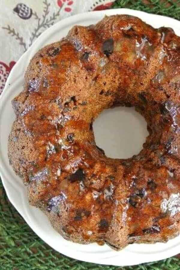 Overhead view of a cropped view of a whole fruitcake on a white plate.