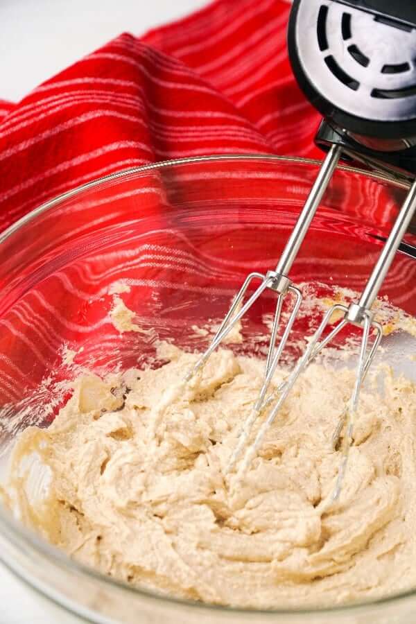 Close up of an electric blender whipping butter and sugars together.