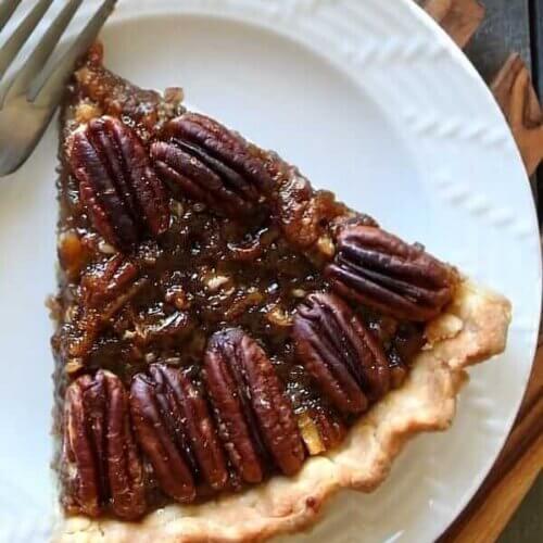 Overhead shot of one slice of pecan pie on a white plate.