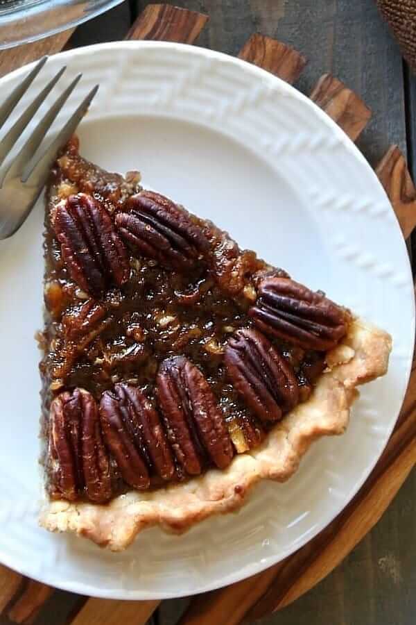 Overhead shot of one slice of pecan pie on a white plate.