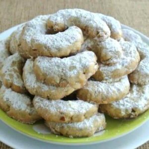 A Square photo of a plate full of shortbread type cookies sprinkled with powdered sugar.