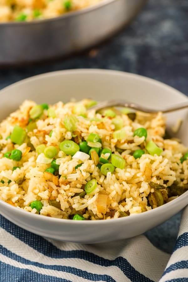 Tigela de caril branco inclinado é preenchida com arroz de caril dourado com um garfo no interior.