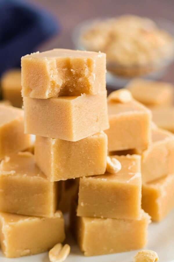 Close up photo of a stack of creamy peanut butter fudge with a bite out of the top square.