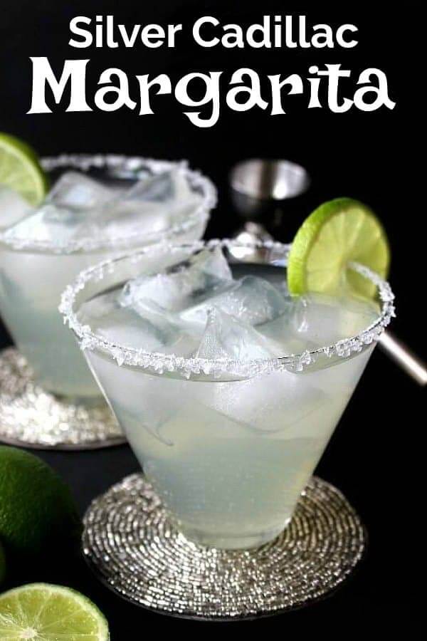 Two flared glasses on silver beaded coasters are filled with lime colored margaritas. Lime rings as garnish.