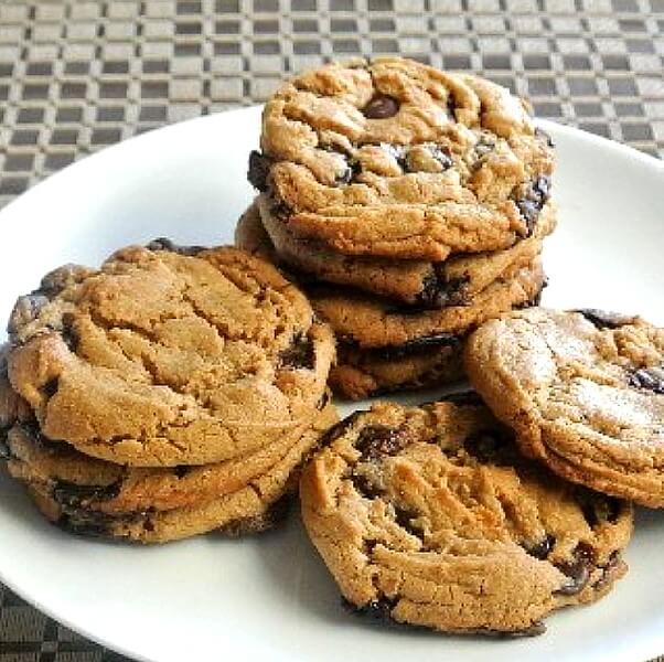 Eight big cookies stacked and spilling all ove a plate.