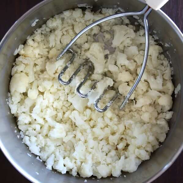Overhead view of fresh cooked cauliflower lightly mashed in a saucepan.