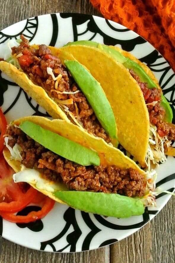 Mexican Sloppy Joe Tacos are three to a plate. Bright filling with bright green avocados are piled high.