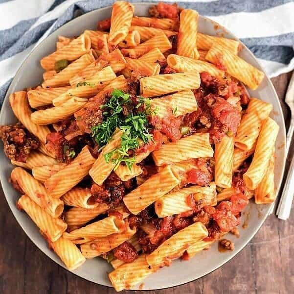 Overhead square photo of a pile of rigatoni and meatless sauce in an off white plate.