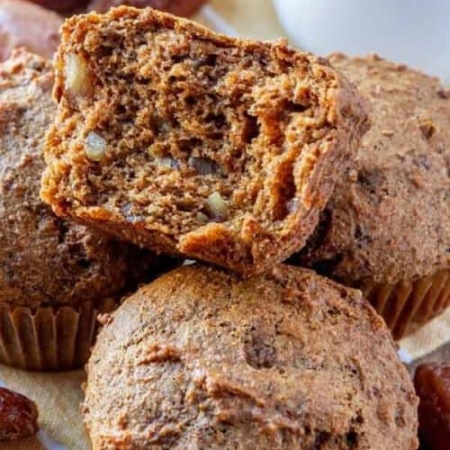 Close-up of an open bran muffin sitting on top of a full muffin.