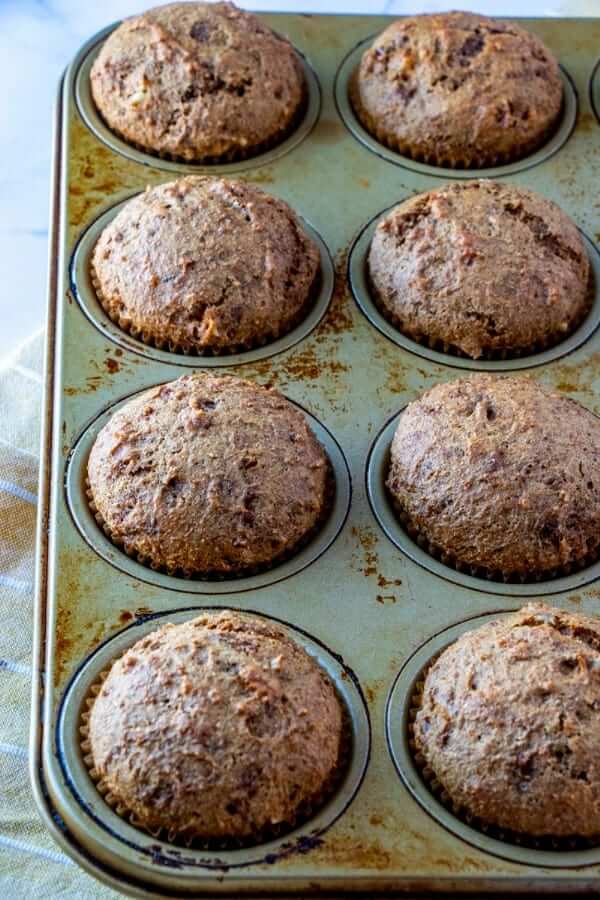 Long angle of big fat baked vegan bran muffins still in their muffin tins.