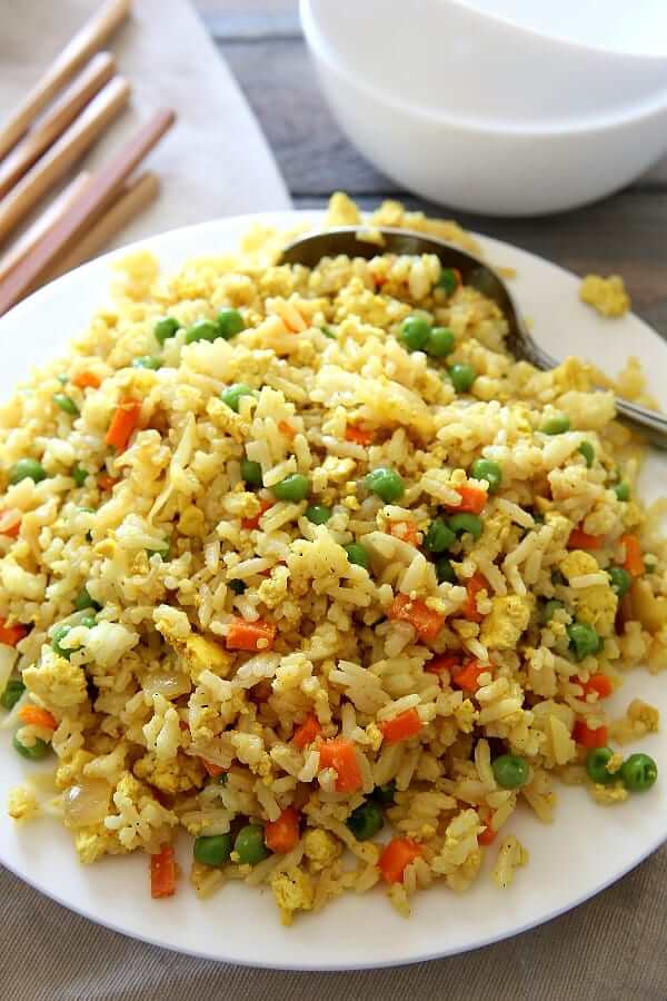 Large bowl full of vegan panda express copycat fried rice to be served with a large serving spoon tucked in the side.
