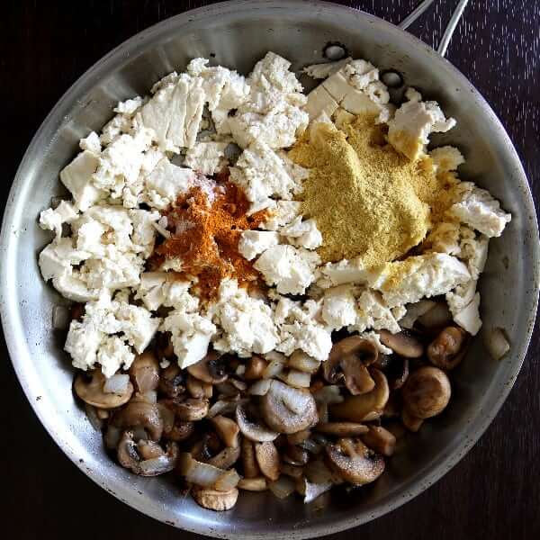 Overhead photo os tofu scrambled eggs in a skillet waiting to be scrambled over heat.