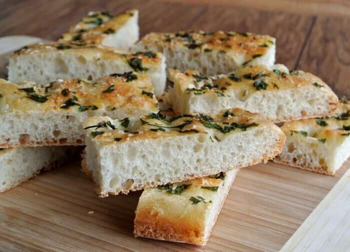 Side view of multiple thin slices of vegan focaccia bread stacked on top of each other..