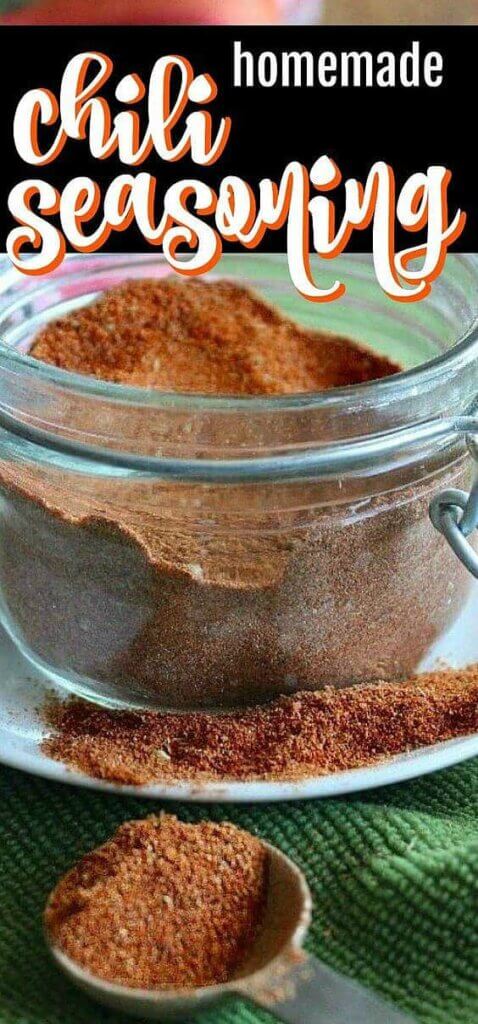 A half pint jar filled with burnt reddish color of spices mixed and on a spoon in front.