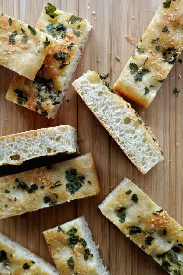 Overhead photo of many two inch slices of a vegan focaccia bread slab sprinkled with oregano.