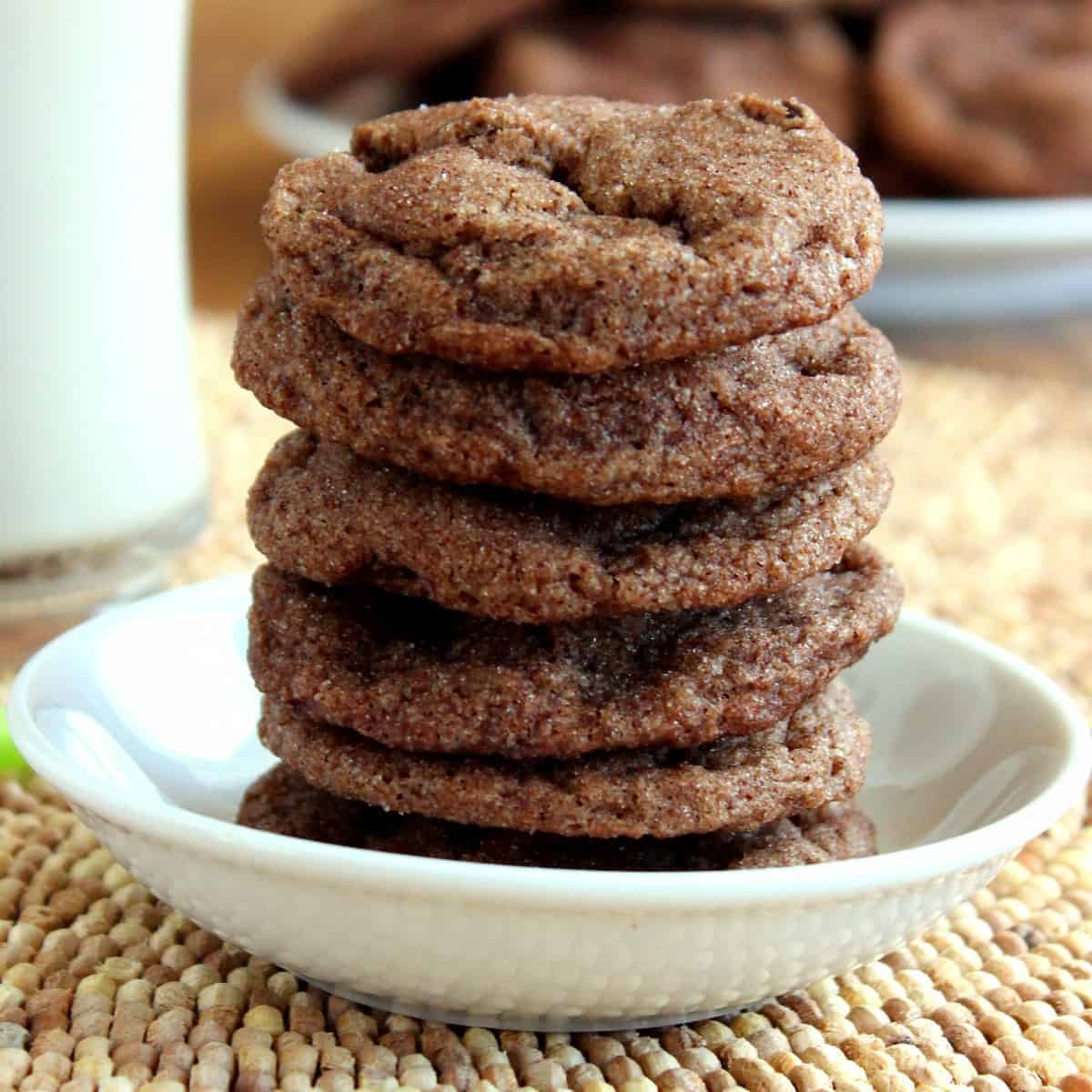 Square photo of a stack of vegan double chocolate chip cookies in a small white bowl.