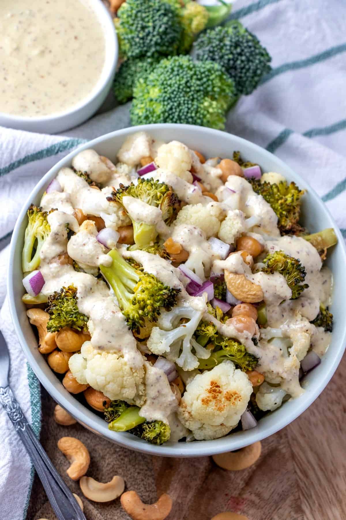 Tilted vegan Buddha bowl full of cauliflower, broccoli, chickpeas and cashews topped with a creamy sauce.