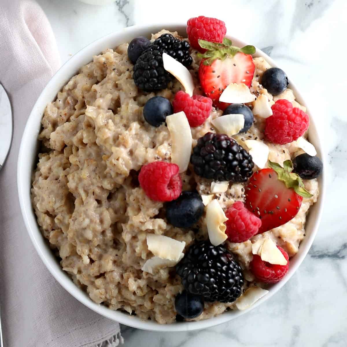 Overhead view of Oatmeal with half the bowl covered with fresh berries and coconut flakes.