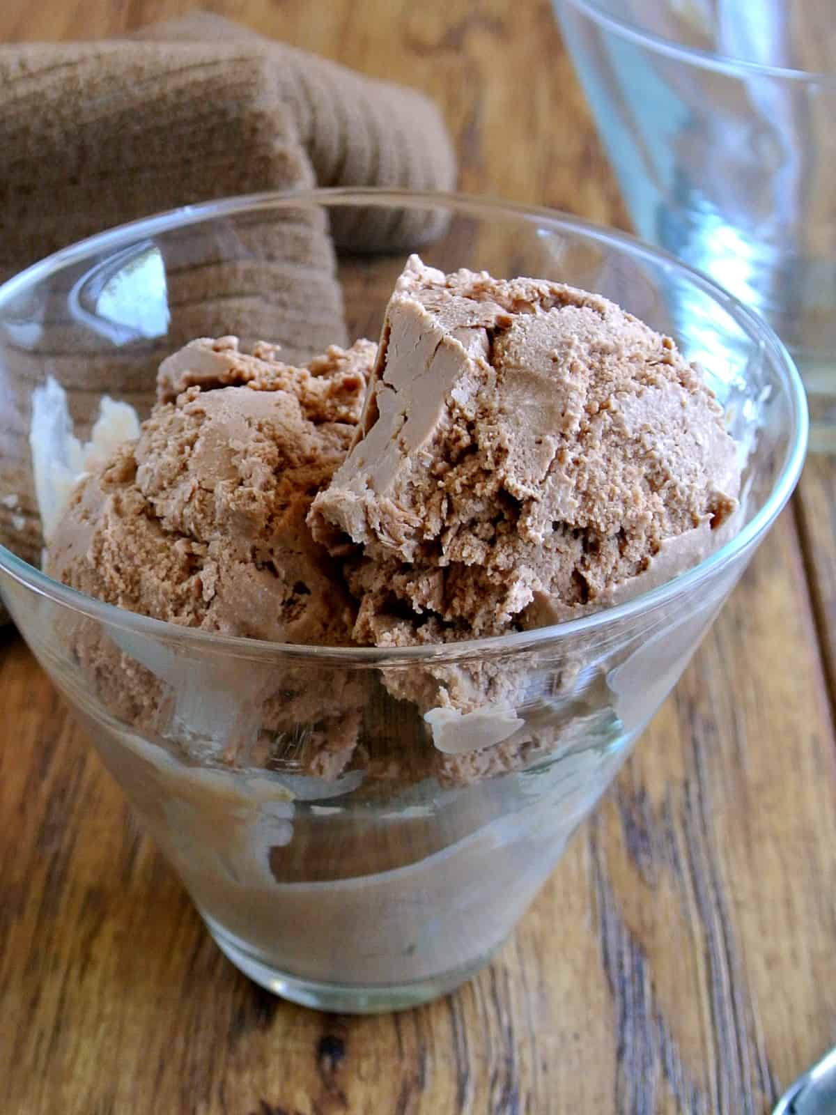 A tilted glass full of homemade frozen treat scoops of deep chocolate.