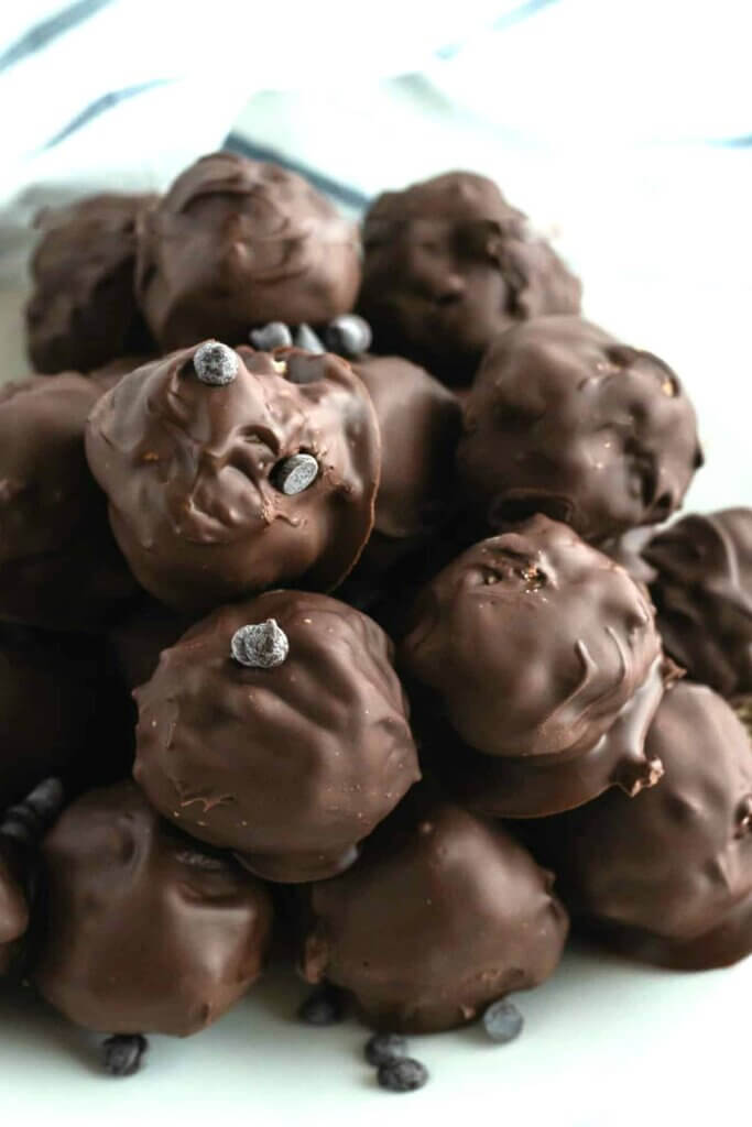 A close-up view of chocolate covered balls with mini chocolate chips sprinkled into the chocolate.