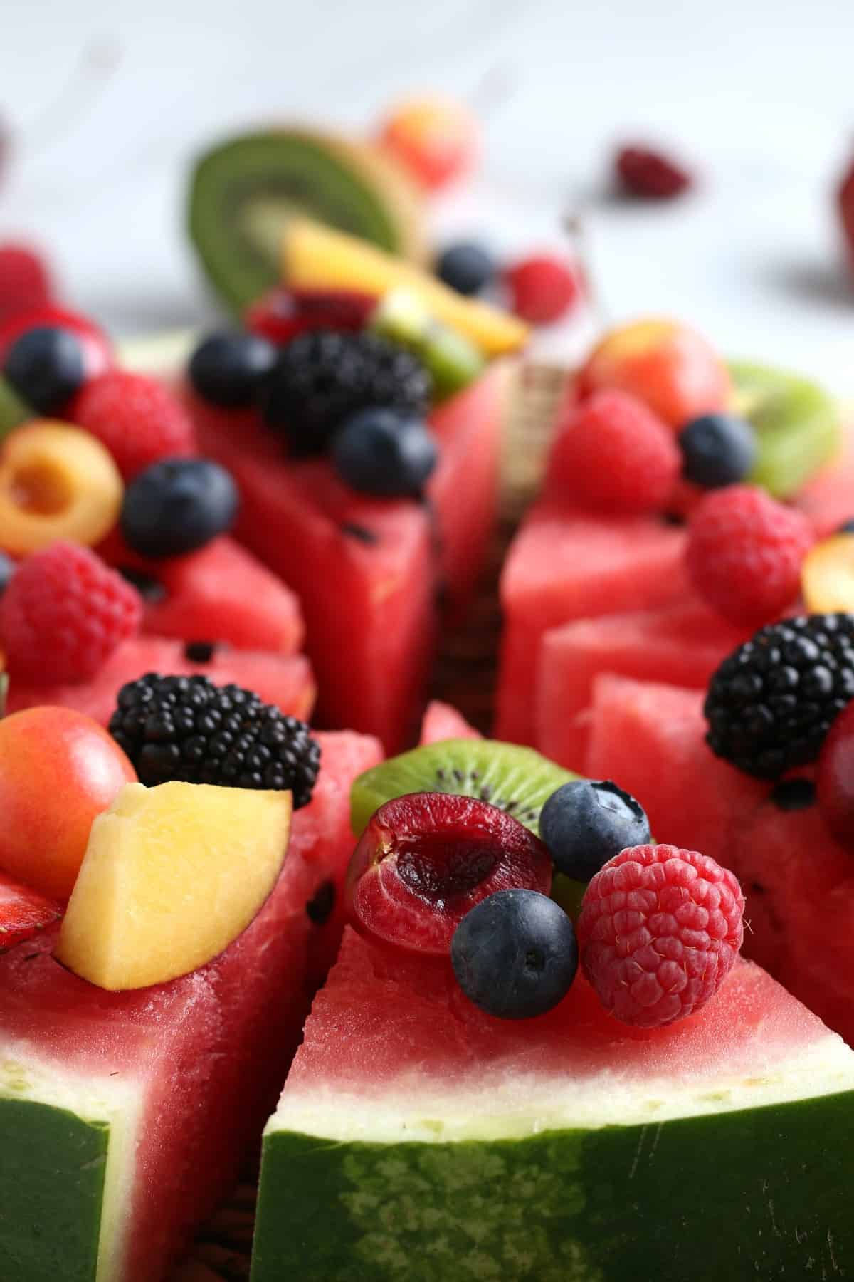 Extremely close photo of the watermelon slice angles and loaded with peaches and berries.
