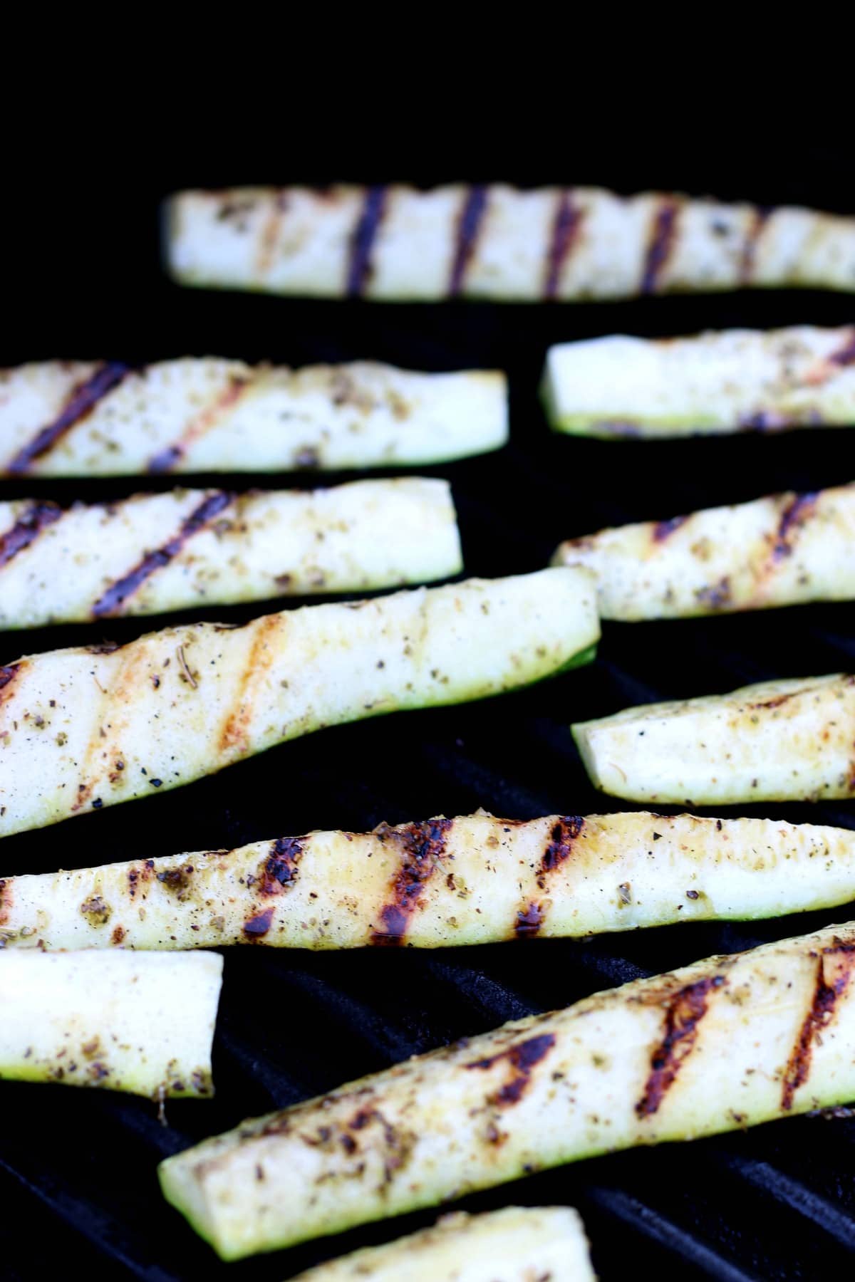 Side angled view of zucchini spear on the grill and with grill marks on the veggies.
