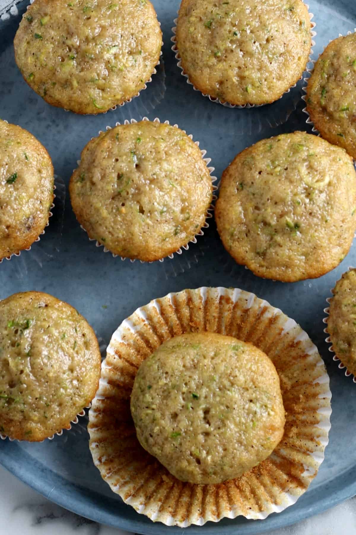 Closeup view of about 7 muffins with one front and center with the paper muffin cup pulled away.