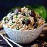 Gorgeous rice with mushrooms and peas is filling a patterned bowl with chopsticks on the side.