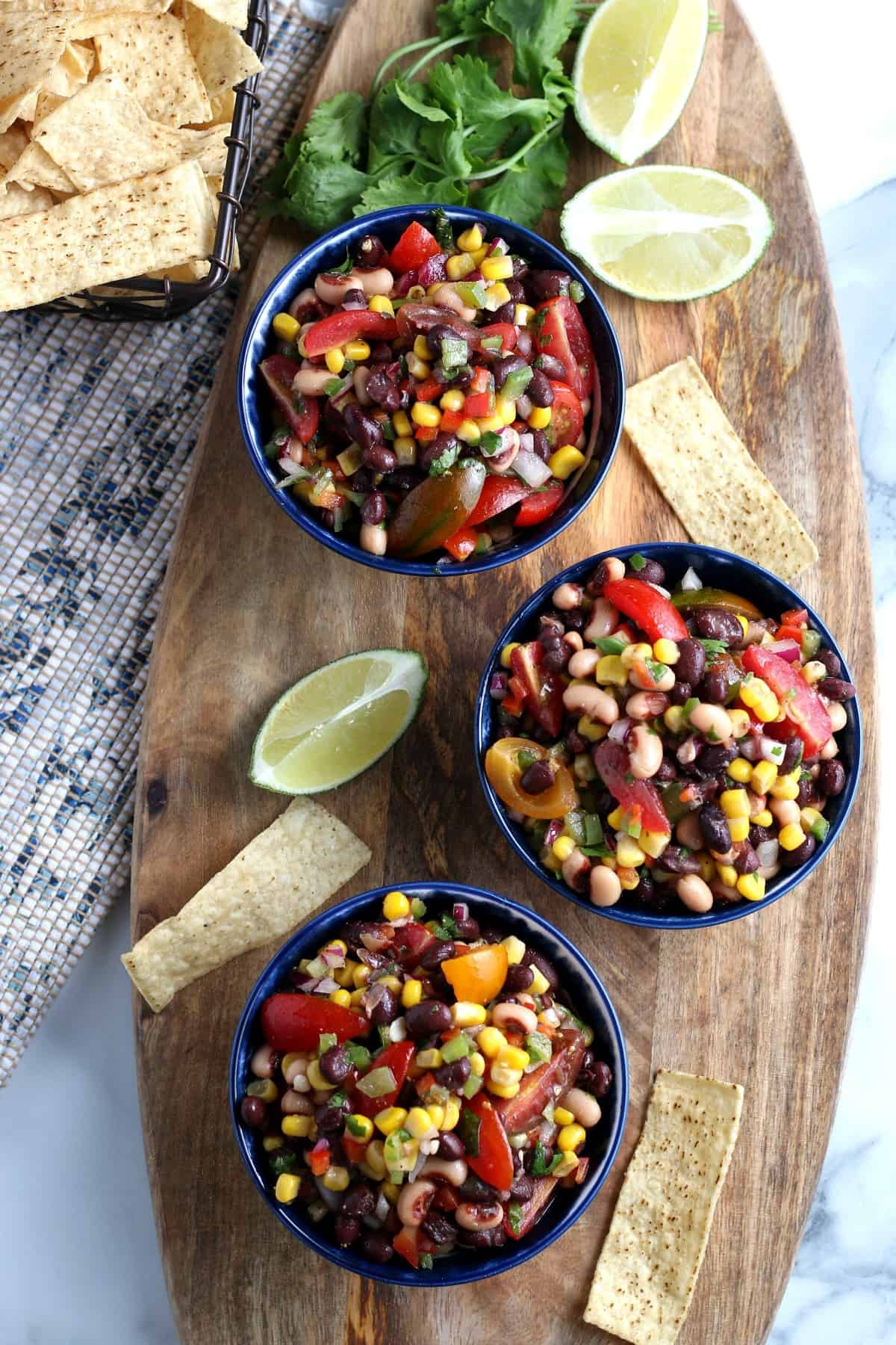 Overhead view of three bowls full of this Texas caviar recipe and a bowl of tortilla strips on the side.