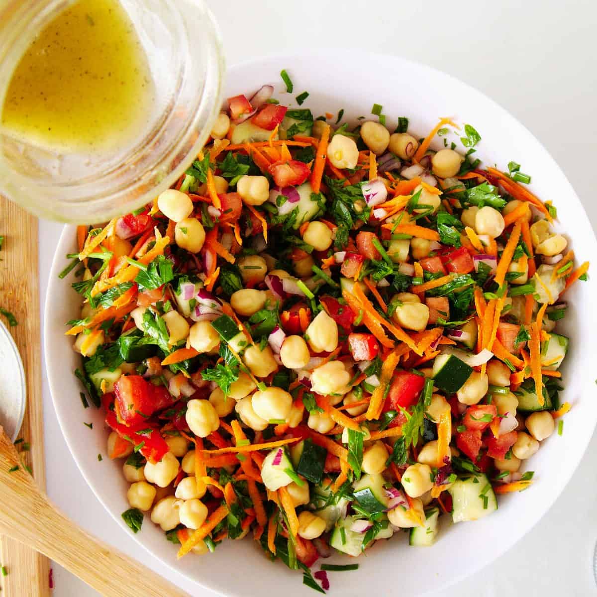 Overhead view of chickpea salad with lemon dressing being poured over the top.