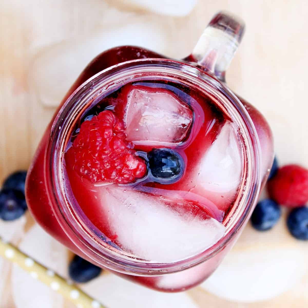 Overhead view and looking down into a glass mug filled with red wine and berries over ice.