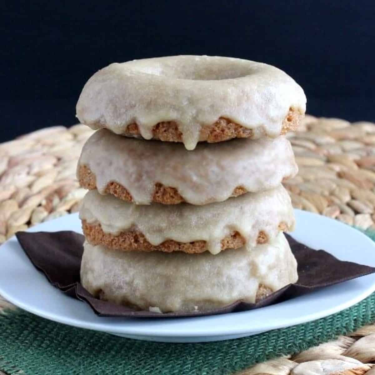 Close up photo of four maple donuts stacked on top of each other with maple icing on each one and dripping down the sides.