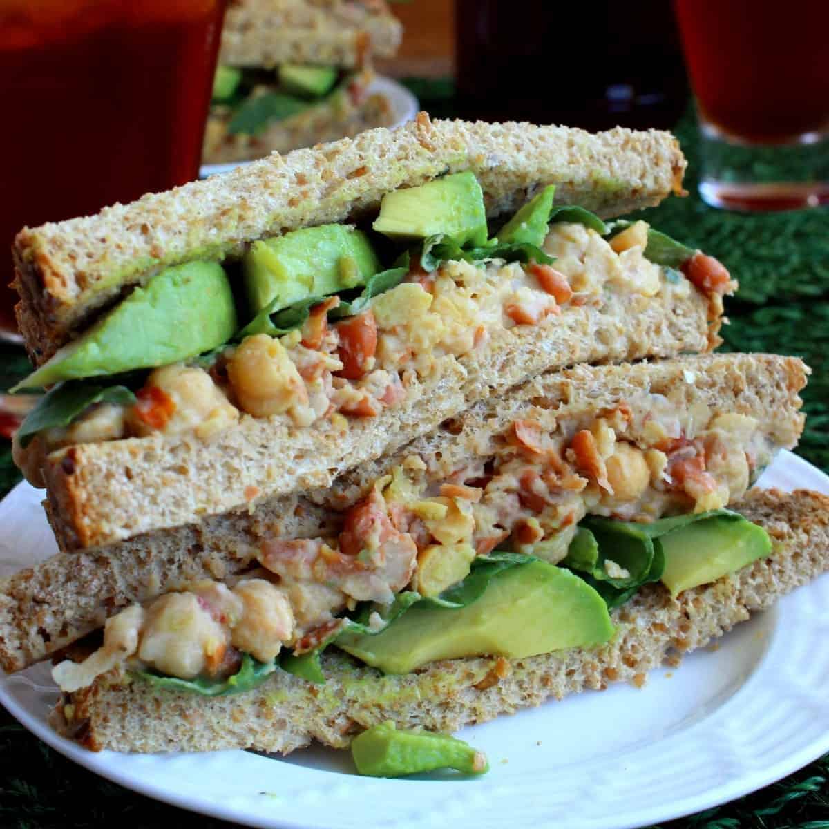 Two chickpea salad sandwich halves stacked on top of each other to show the veggies inside.