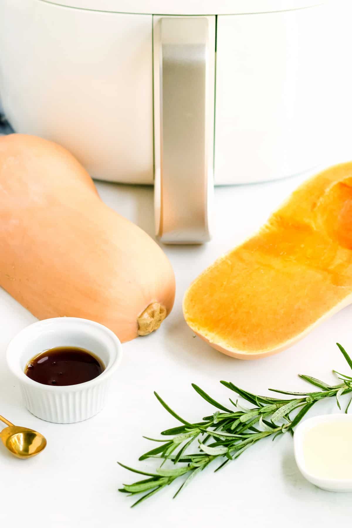 Six ingredients for air fryer butternut squash with air fryer in the back.