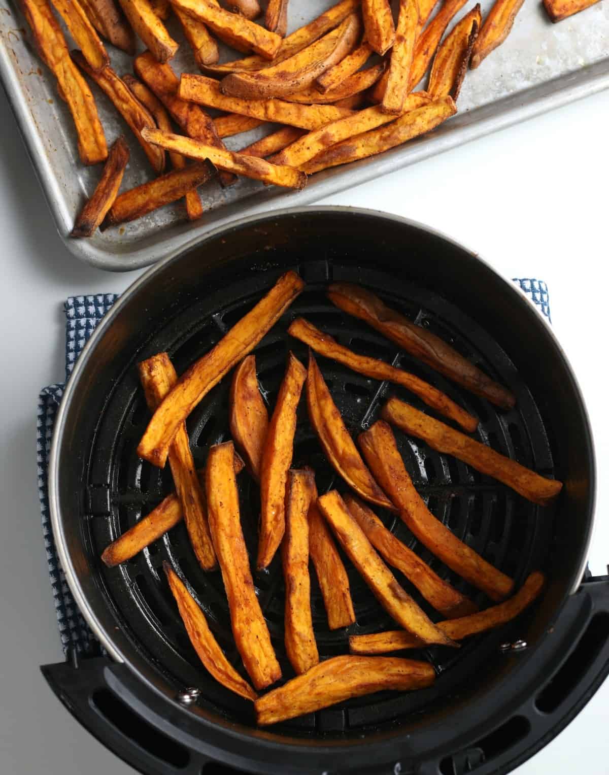 Looking down in an air fryer at cooked sweet potato fries.