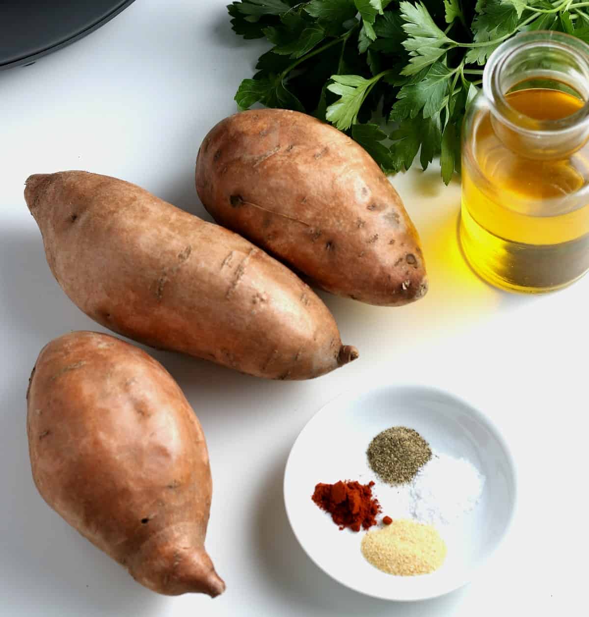 Ingredients for fries including spices, oil and sweet potatoes.