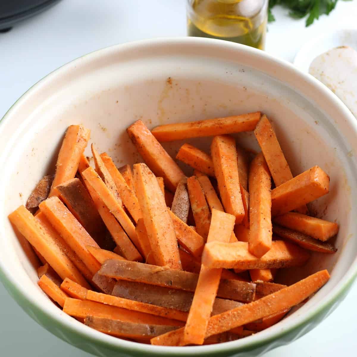 Matchstick veggies in a mixing bowl and tossed with oil and seasonings.