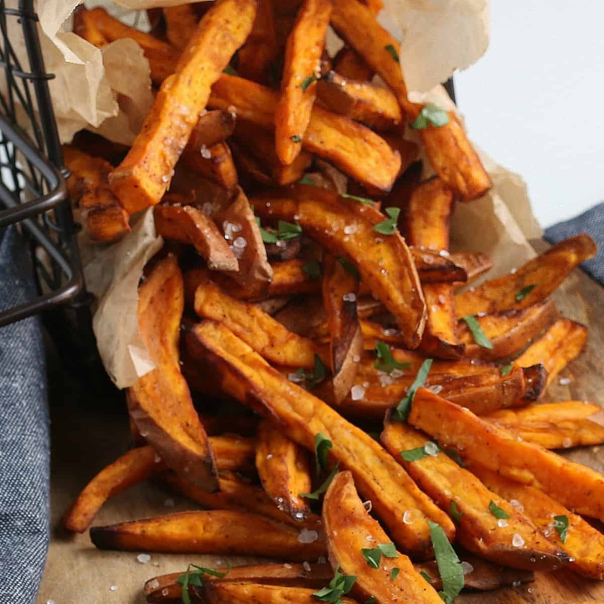 Closup of sweet potato fries dumped out on a wooden board.