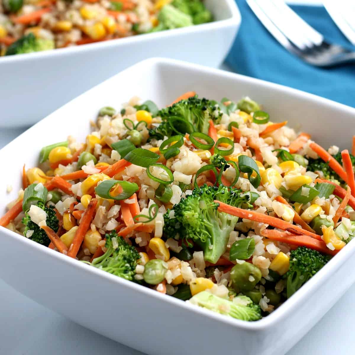 Square white bowl fulled with colorful Cauliflower Rice Stir Fry.