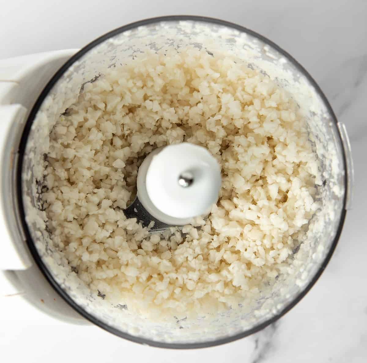 Looking down into a food processor after the cauliflower has been processed into rice.