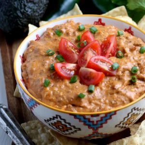 Full bowl of refried bean dip tomatoes and chives garnishing the top.