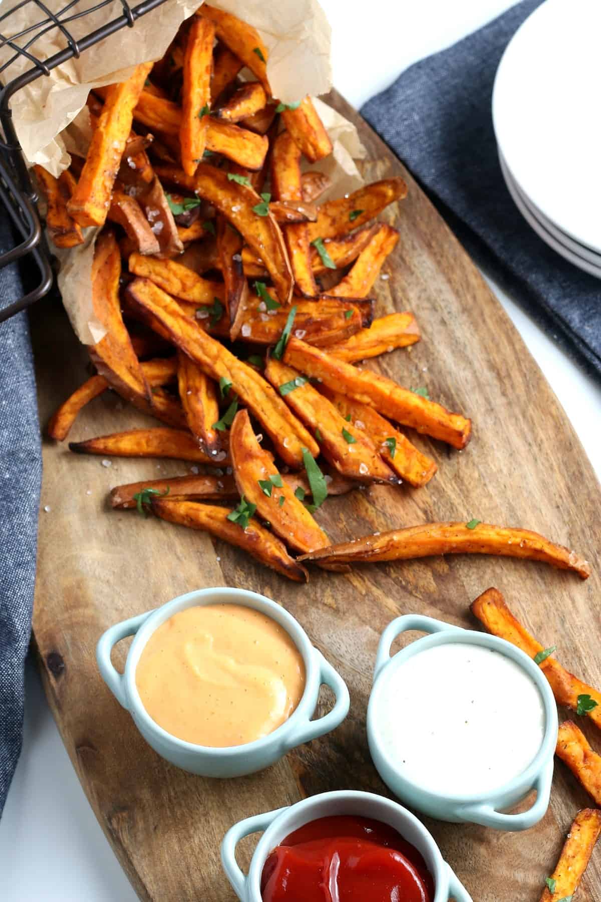 Overhead view of sweet potato fries and three dipping sauces.