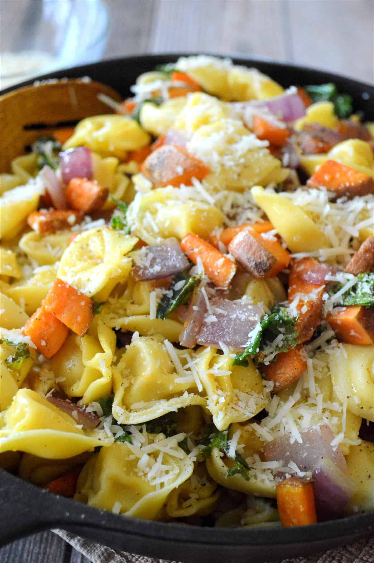 Vegan cheese Tortellini pasta and vegetables mixed together n a skillet.