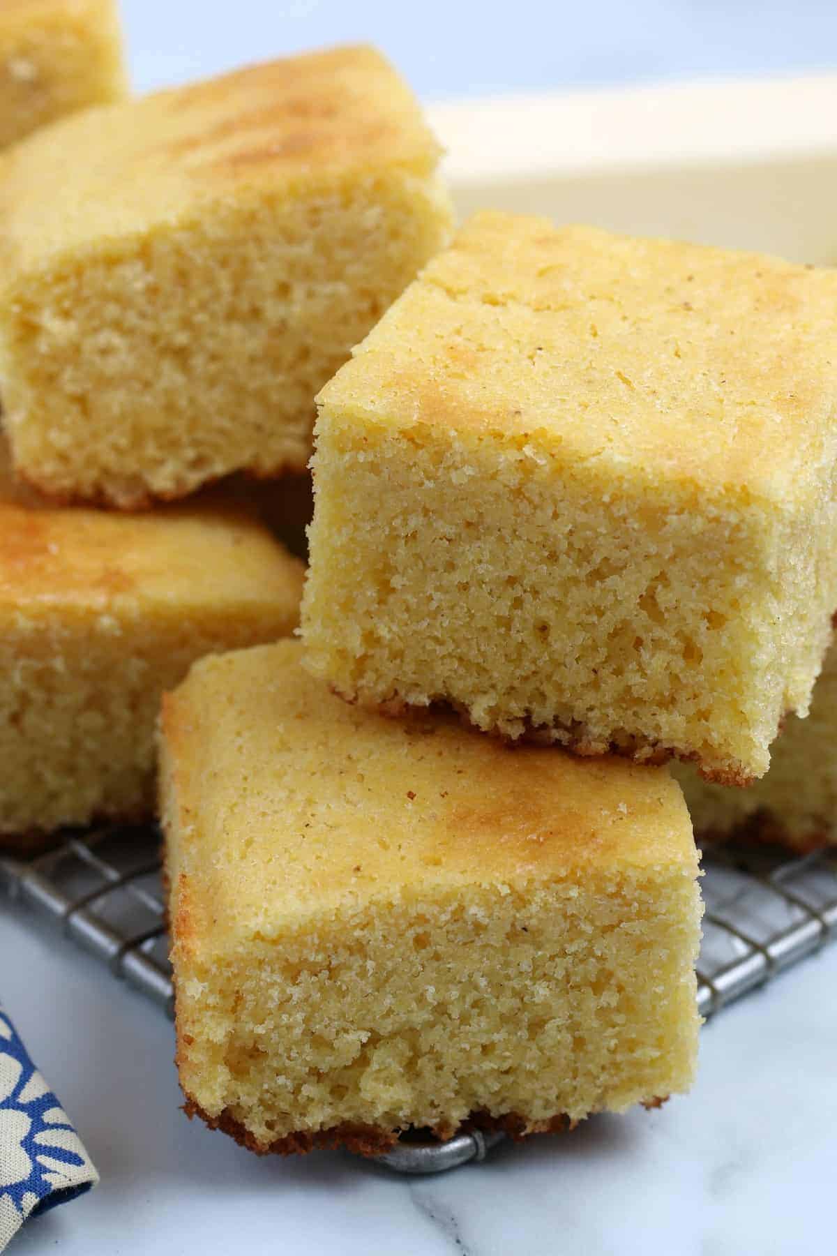 Close up of many squares of cornbread stacked on top of each other.