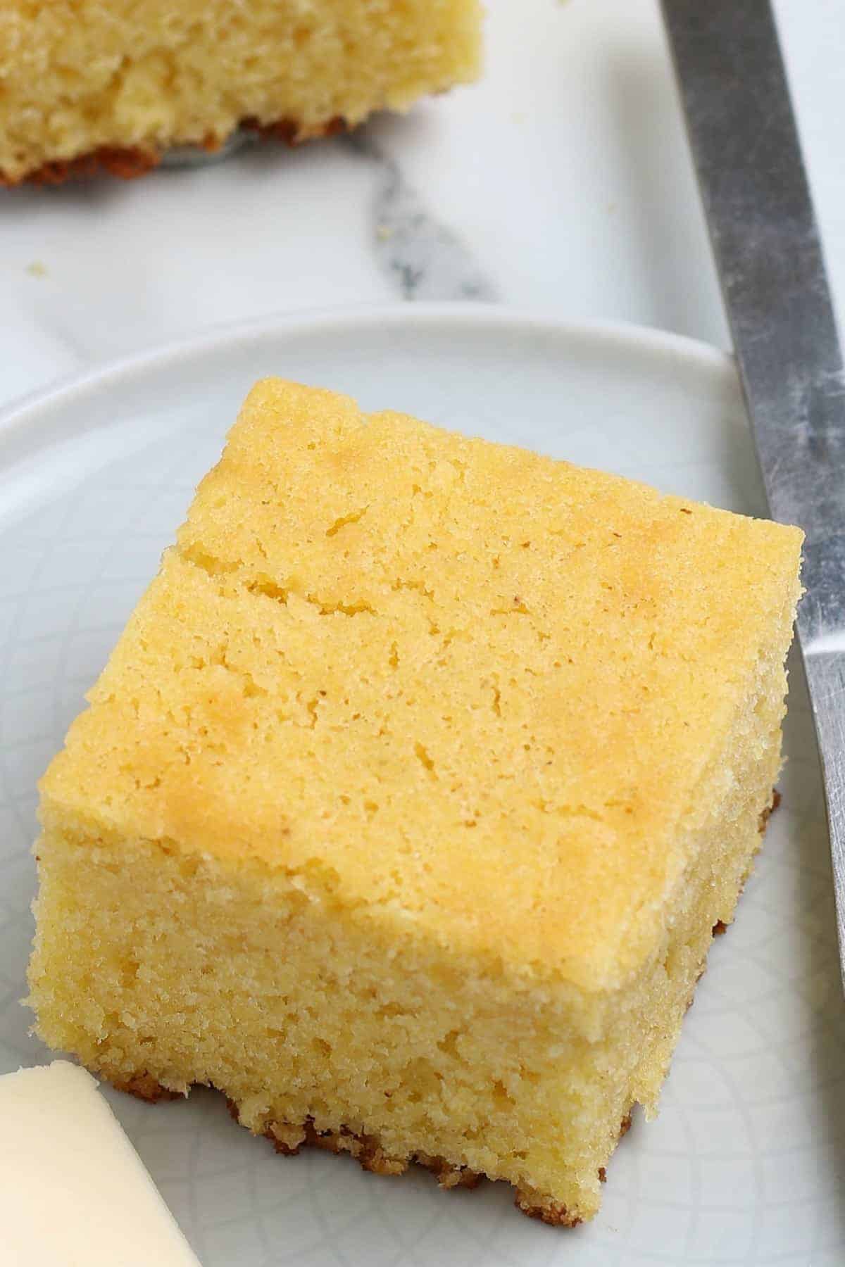 Angled overhead view of a single cut cornbread next to many more.
